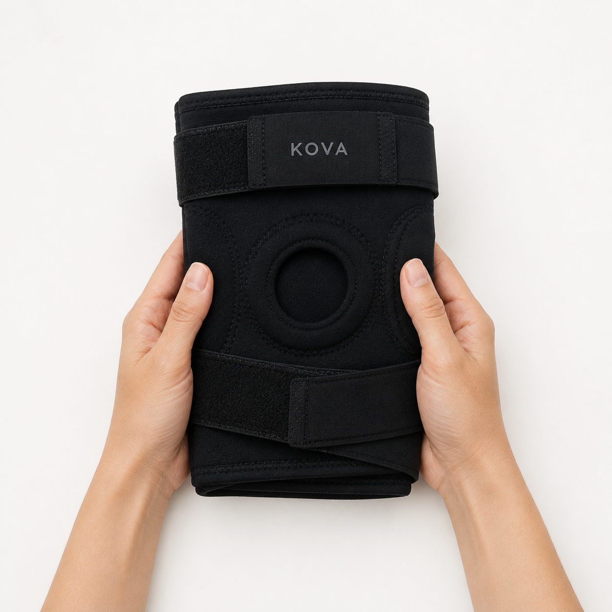 Hands holding the KOVA knee support against a white background